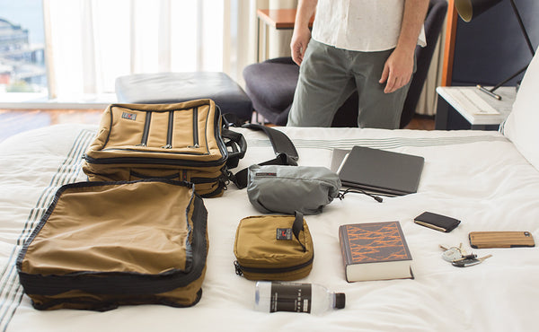 A Tri-Star with a Tri-Star Packing Cube Backpack, Size 4 Travel Stuff Sack, Spiff Kit, laptop and cover, bottle of water, wallet, keys, phone, and hardback novel